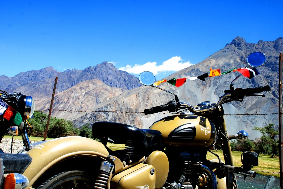 A Royal Enfield parked under prayer flags in the mountains