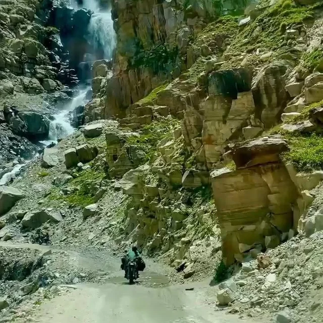 A rider on the road under a waterfall
