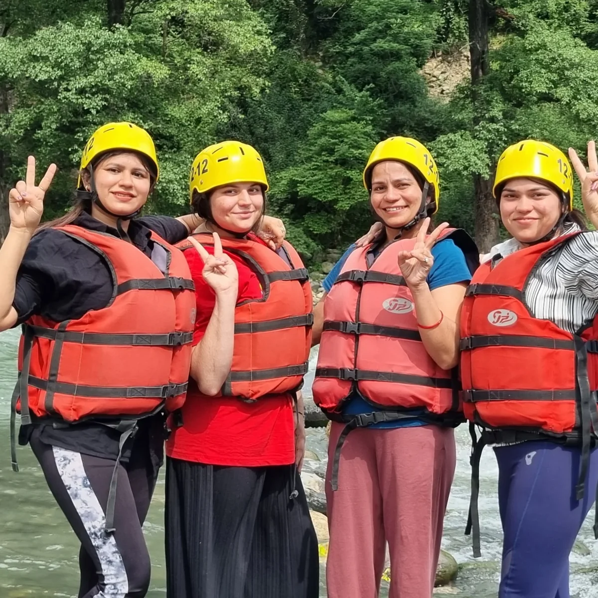 Four friends in helmets and life jackets before a rafting run