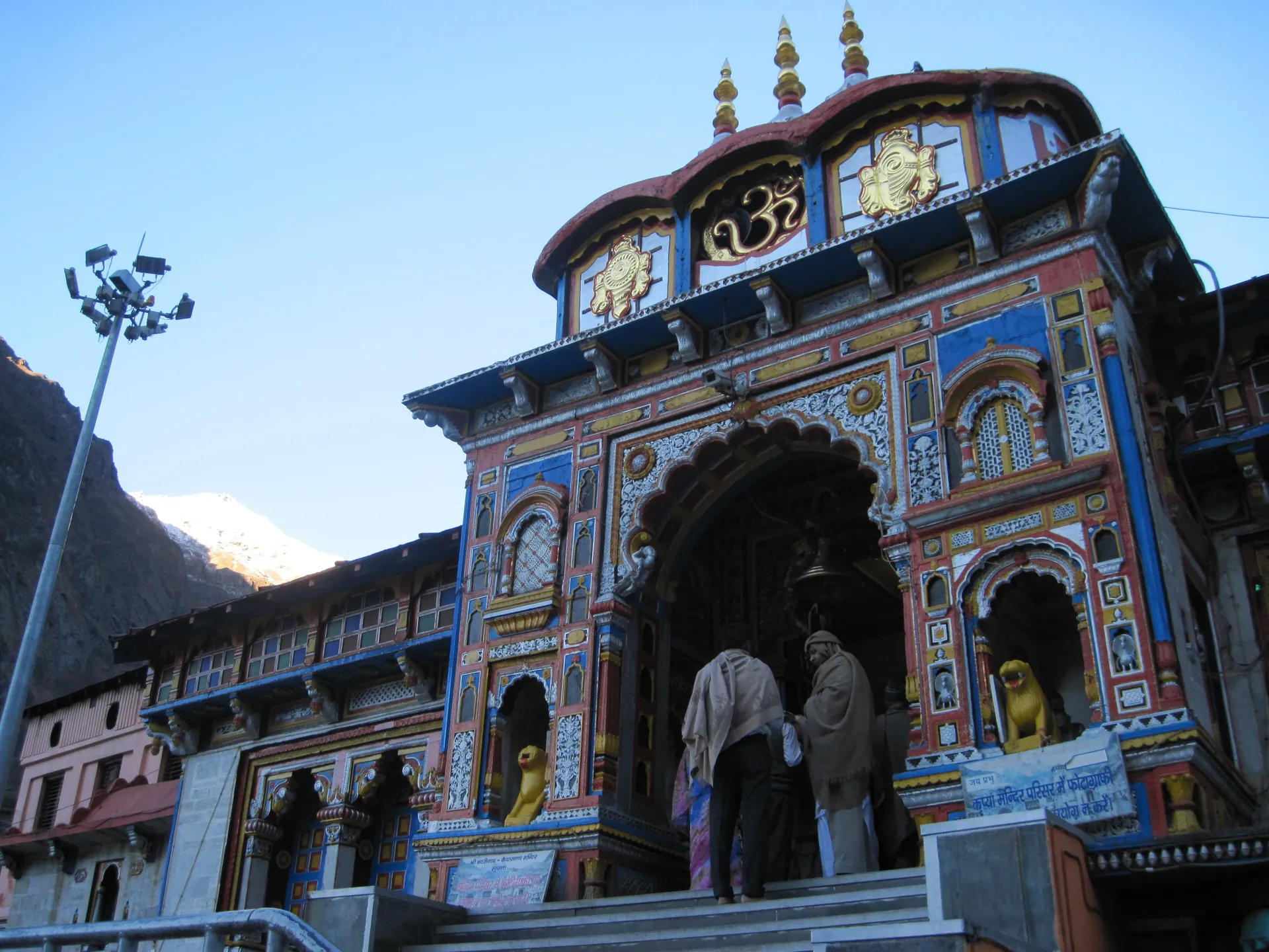 The carved and painted gateway of the Badrinath Temple seen from below in early morning light
