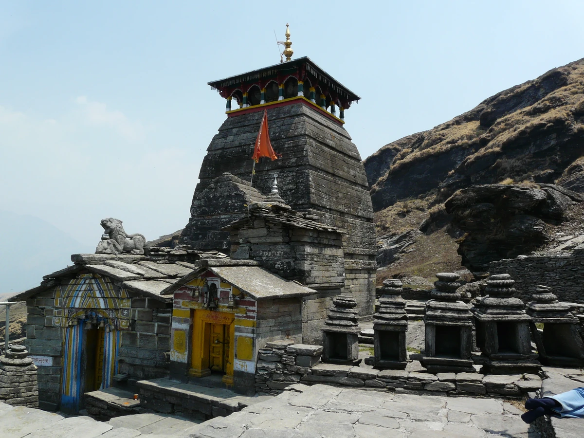 The grey stone Tungnath Temple on a rocky ridge under a clear blue sky
