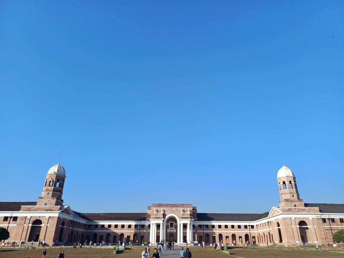 The long red-brick Forest Research Institute with white columns and two domed towers across a wide lawn