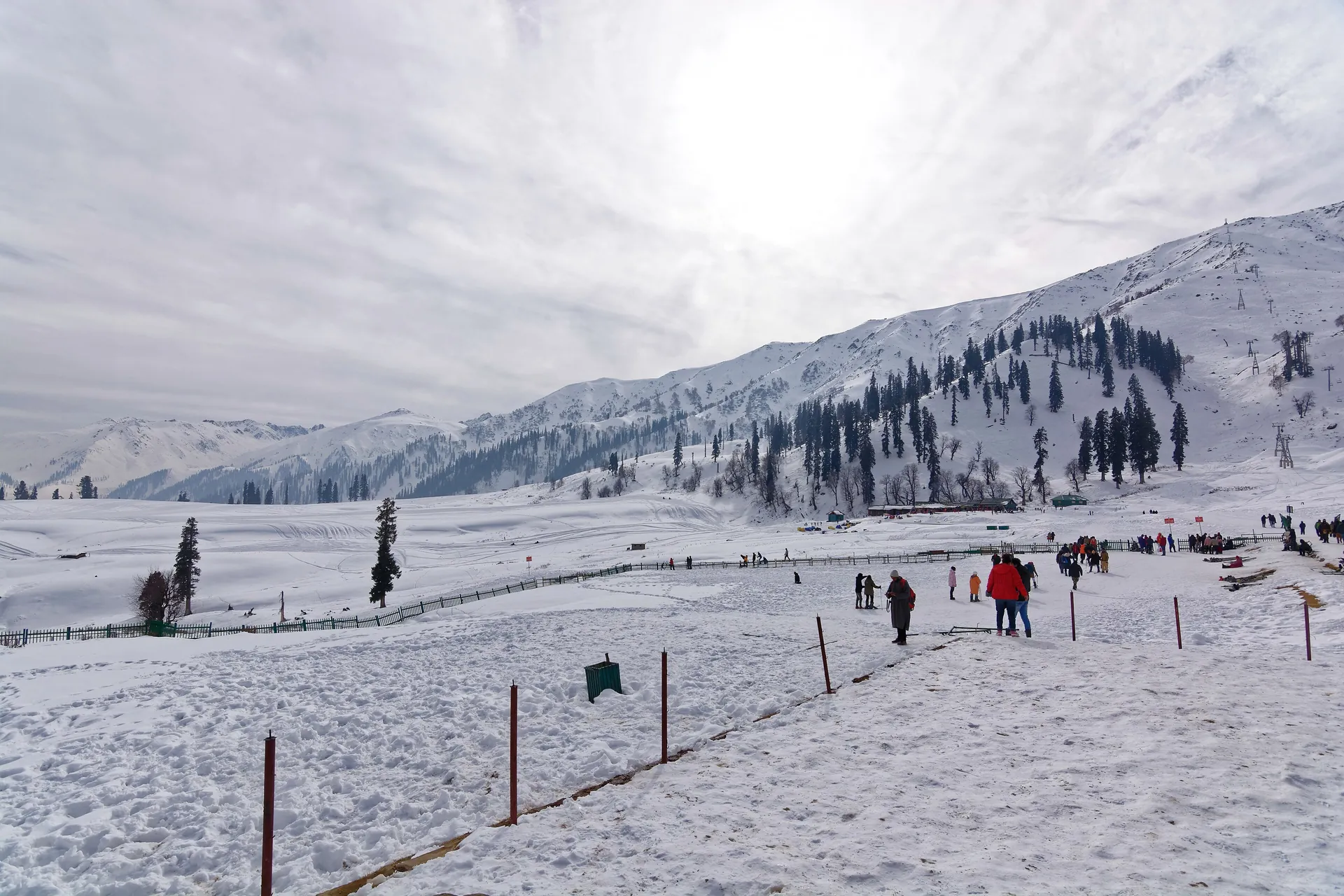 Visitors walking across the snowy Kongdoori bowl beneath a ridge on a bright winter day