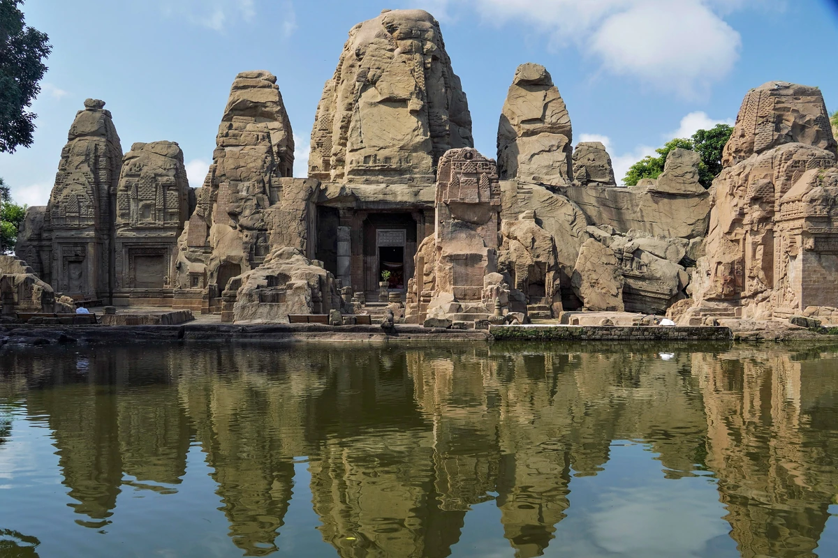 The rock-cut Masrur temples with their carved spires reflected in the still water of the sacred pool