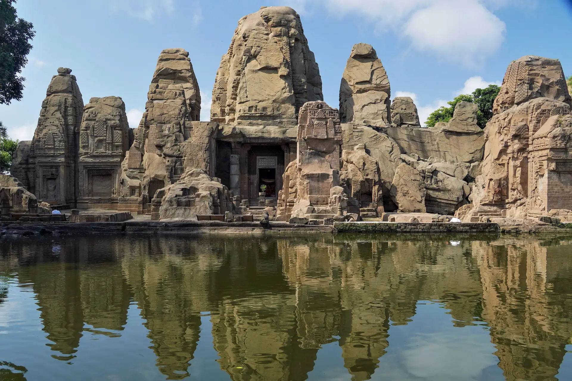 The rock-cut Masrur temples with their carved spires reflected in the still water of the sacred pool