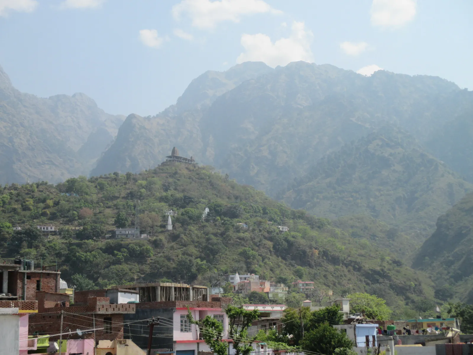 Houses of Katra in the foreground with a small temple on a green hilltop and the high Trikuta ridges behind