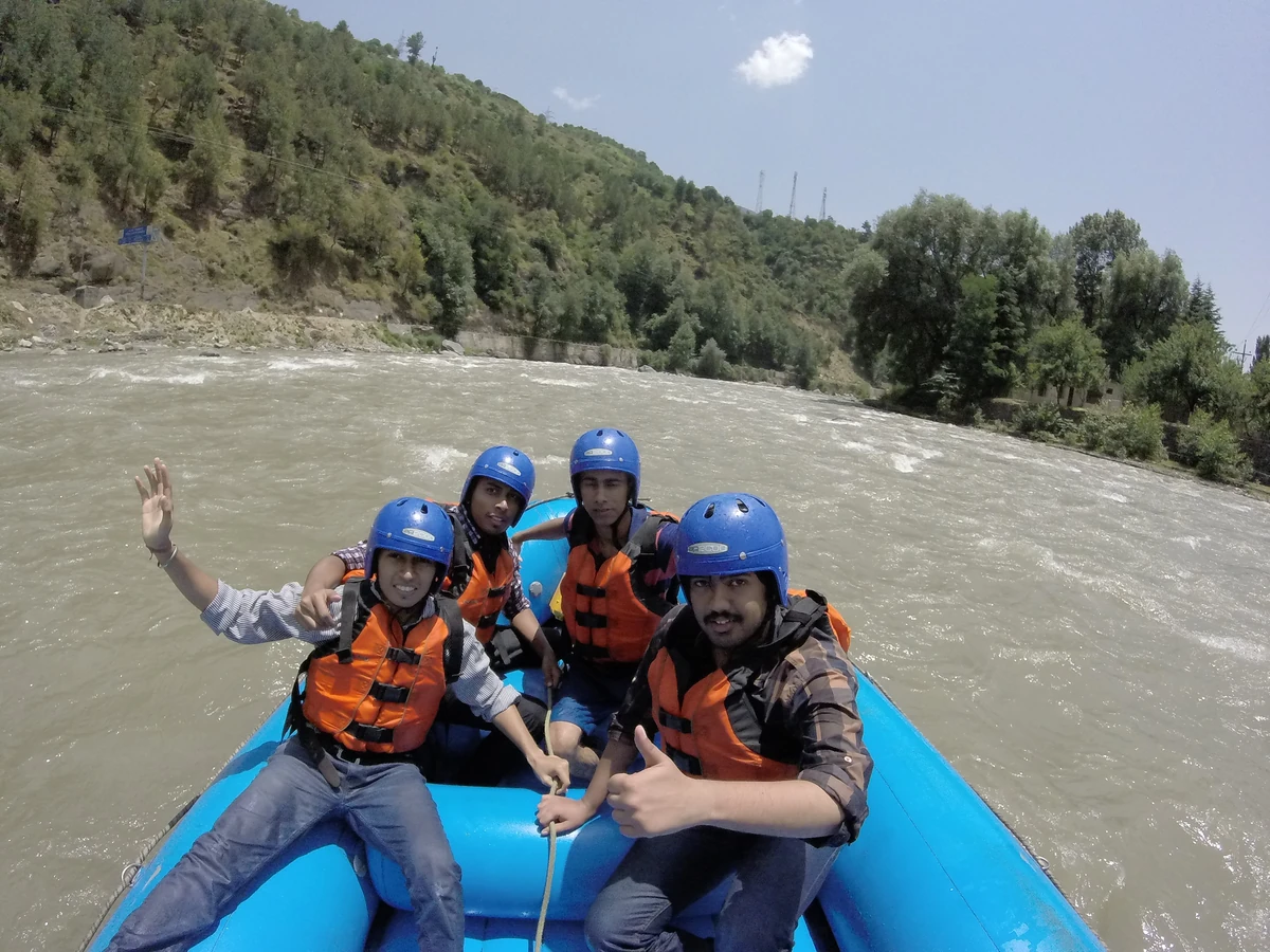 A raft with paddlers in helmets on the Beas