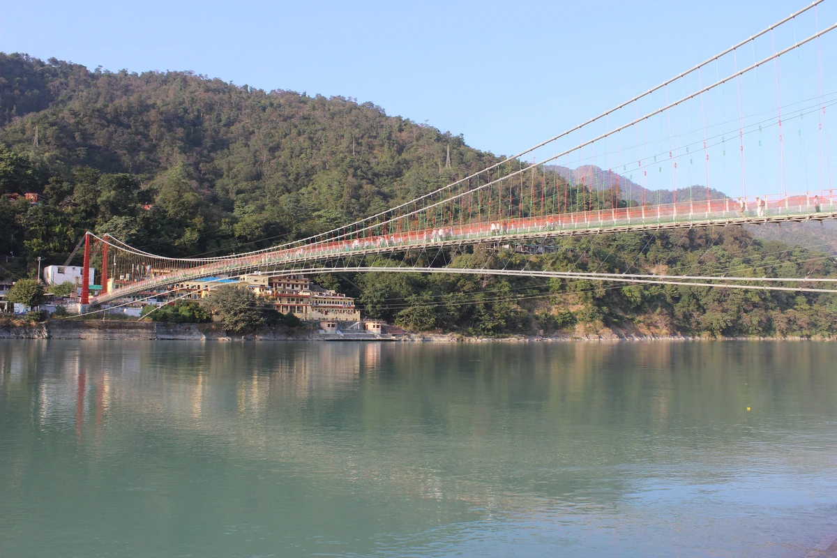 The Lakshman Jhula suspension bridge over the green Ganges below forested hills