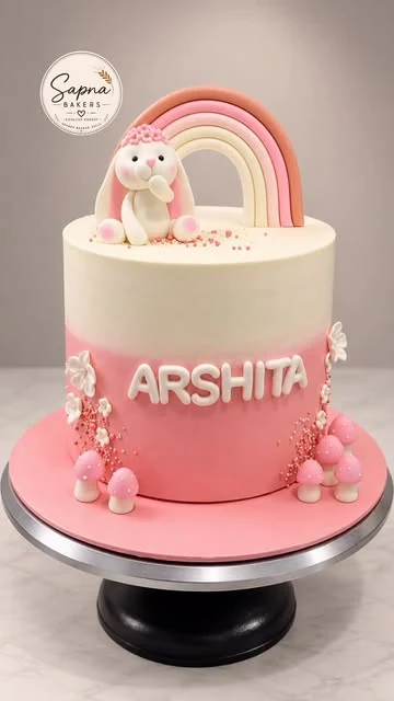 A pink cake with a bunny on a rainbow