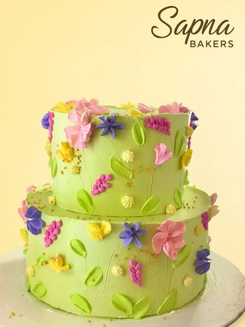 A two-tier green cake covered in sugar flowers