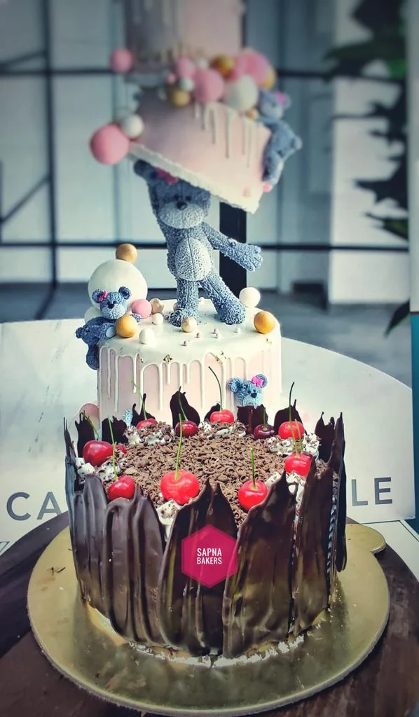 A chocolate cake with a teddy bear on top