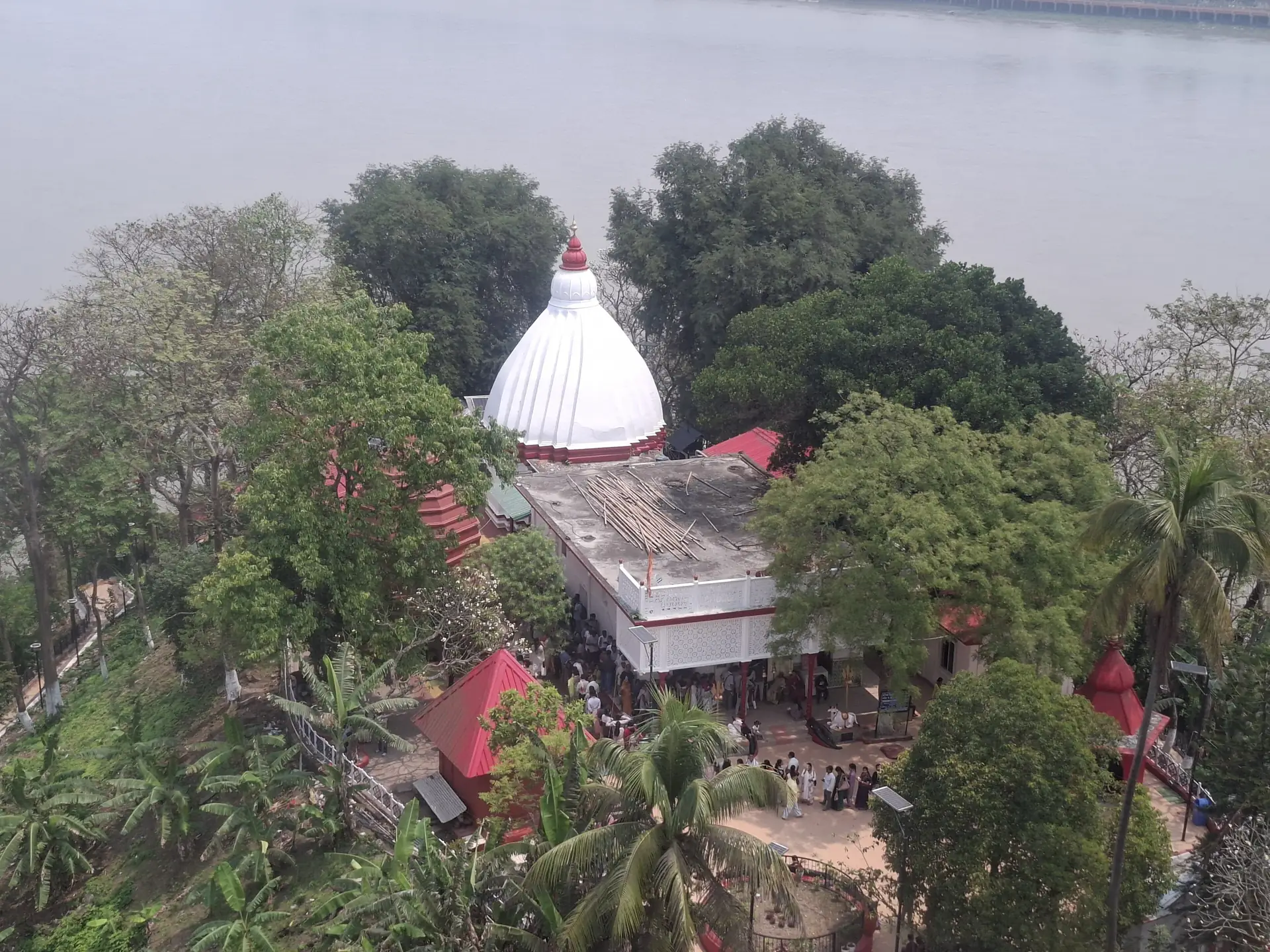 The white dome of the Umananda temple among trees on Peacock Island, seen from above with the Brahmaputra behind