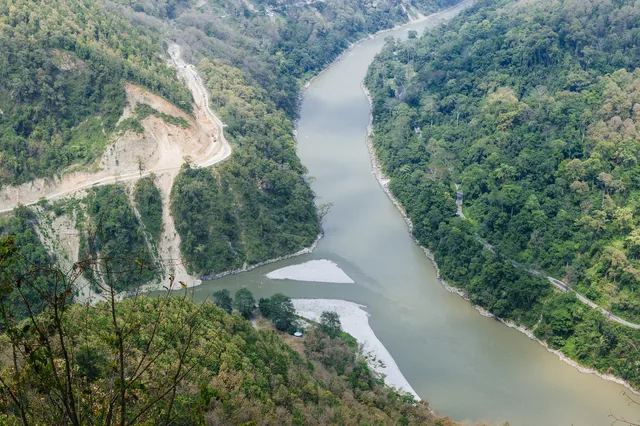 The grey-green Teesta river running through a steep forested gorge, seen from a viewpoint above the confluence with the Rangeet