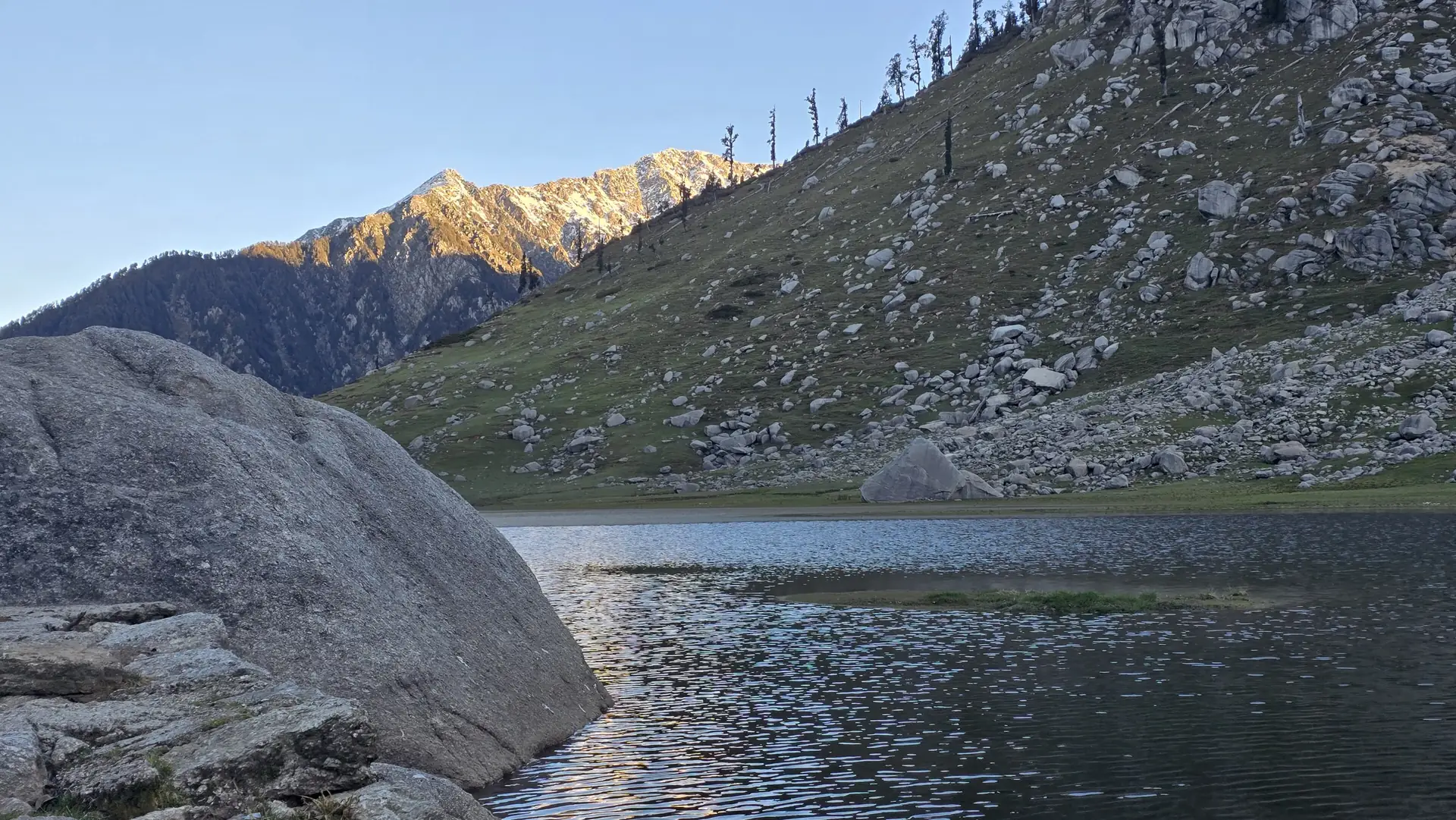 Kareri Lake in its bowl below a rocky ridge with a rose-lit peak behind
