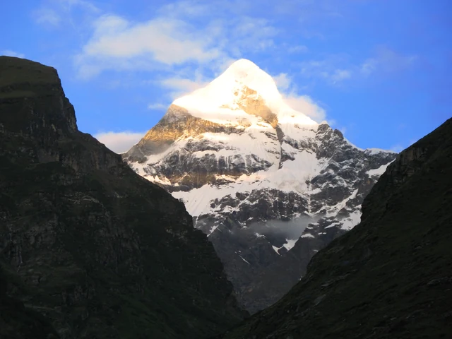 The snow pyramid of Nilkantha peak glowing above dark valley walls, seen from Badrinath