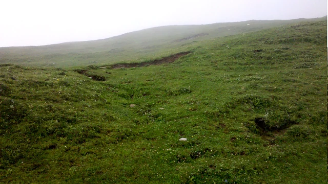 The grass slopes of Raghupur Garh under a pale sky