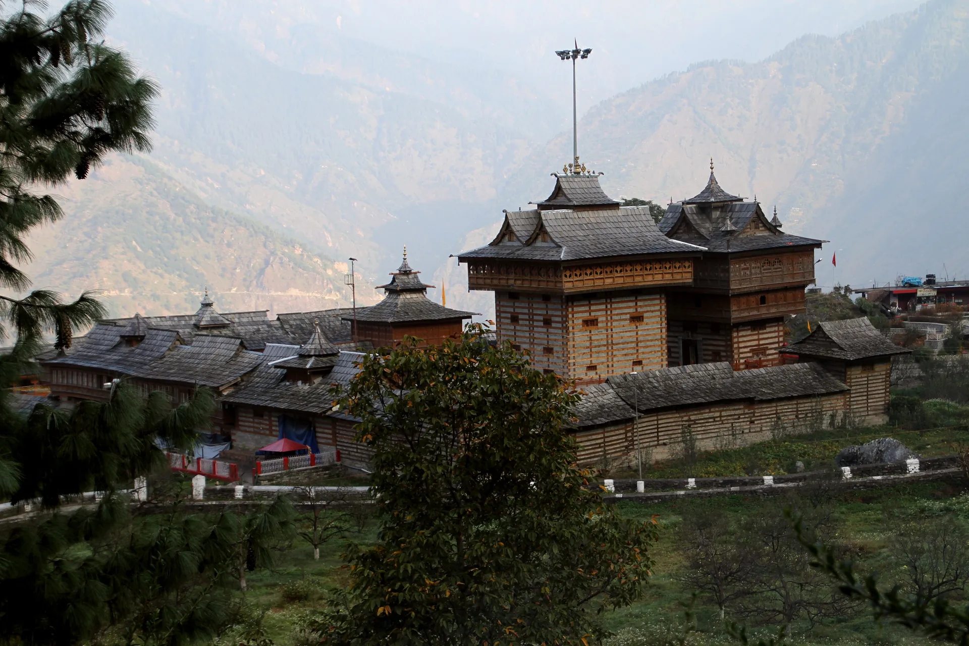 The Bhimakali Temple at Sarahan seen across a slope with hazy mountains behind