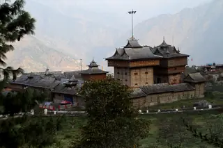 The Bhimakali Temple at Sarahan seen across a slope with hazy mountains behind