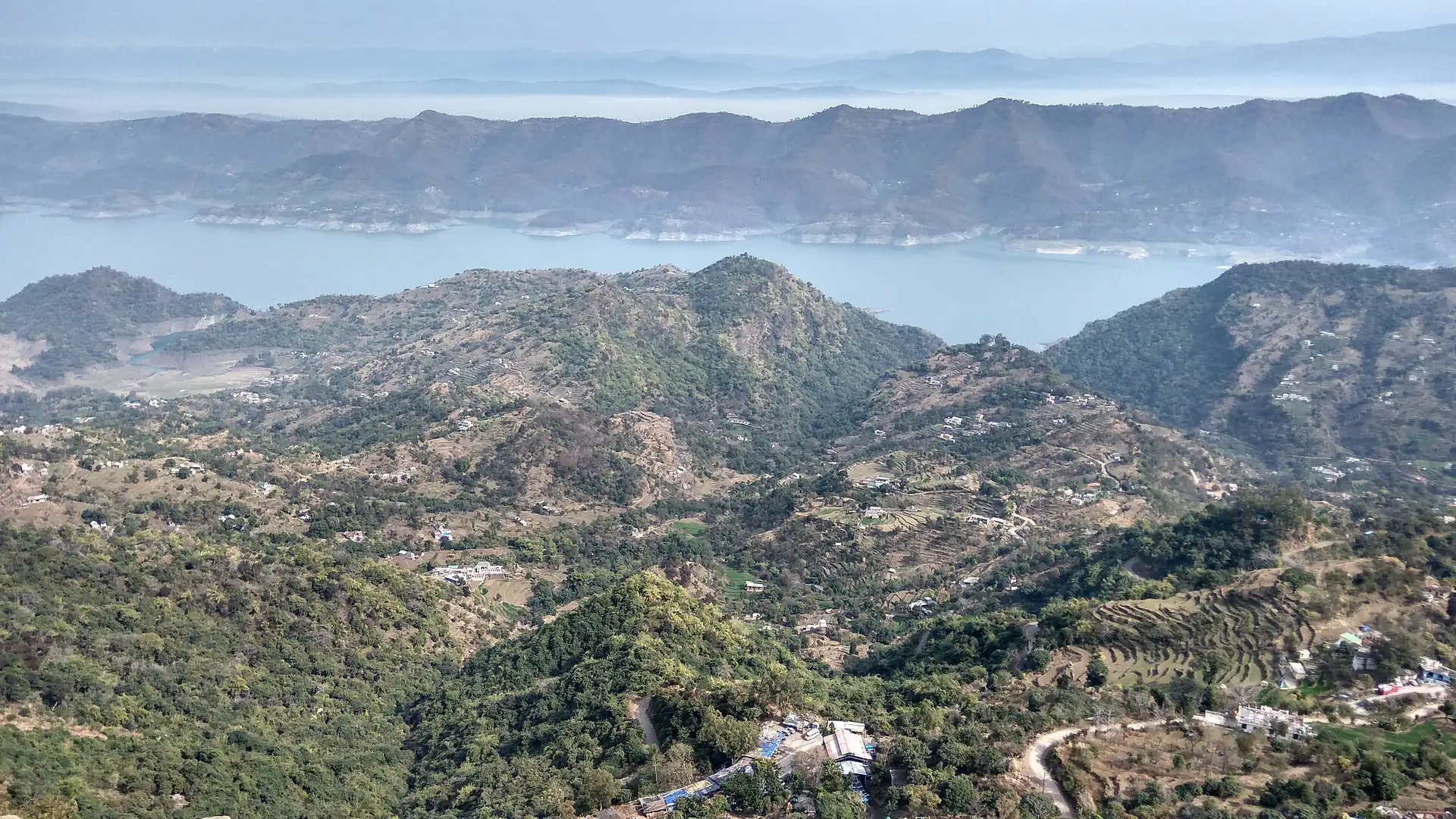 The wide blue water of Gobind Sagar between low green hills