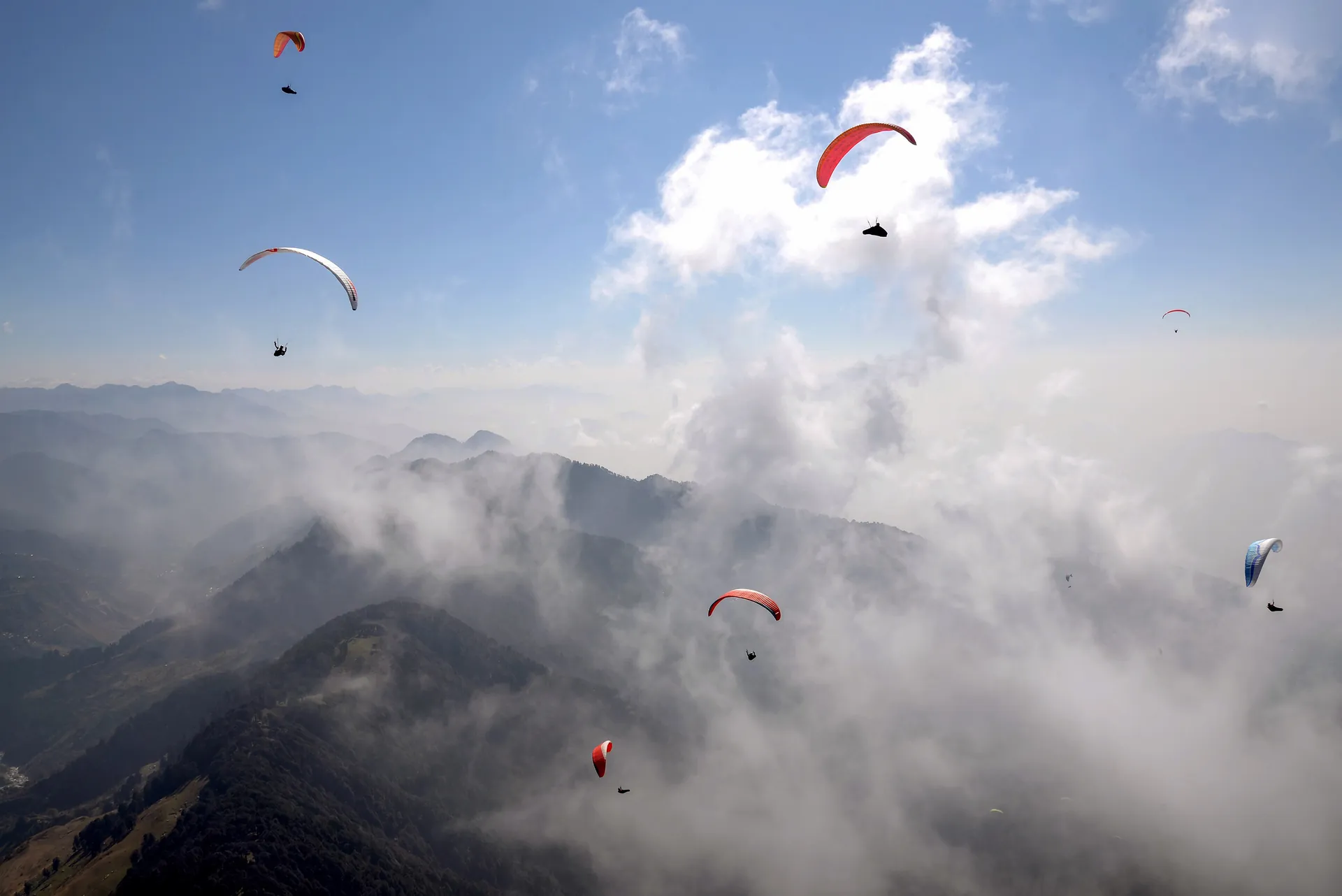 Several paragliders in the air over the hills above Bir