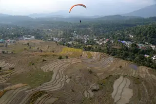 Bir from the air, with terraced fields, the village and a paraglider over the valley