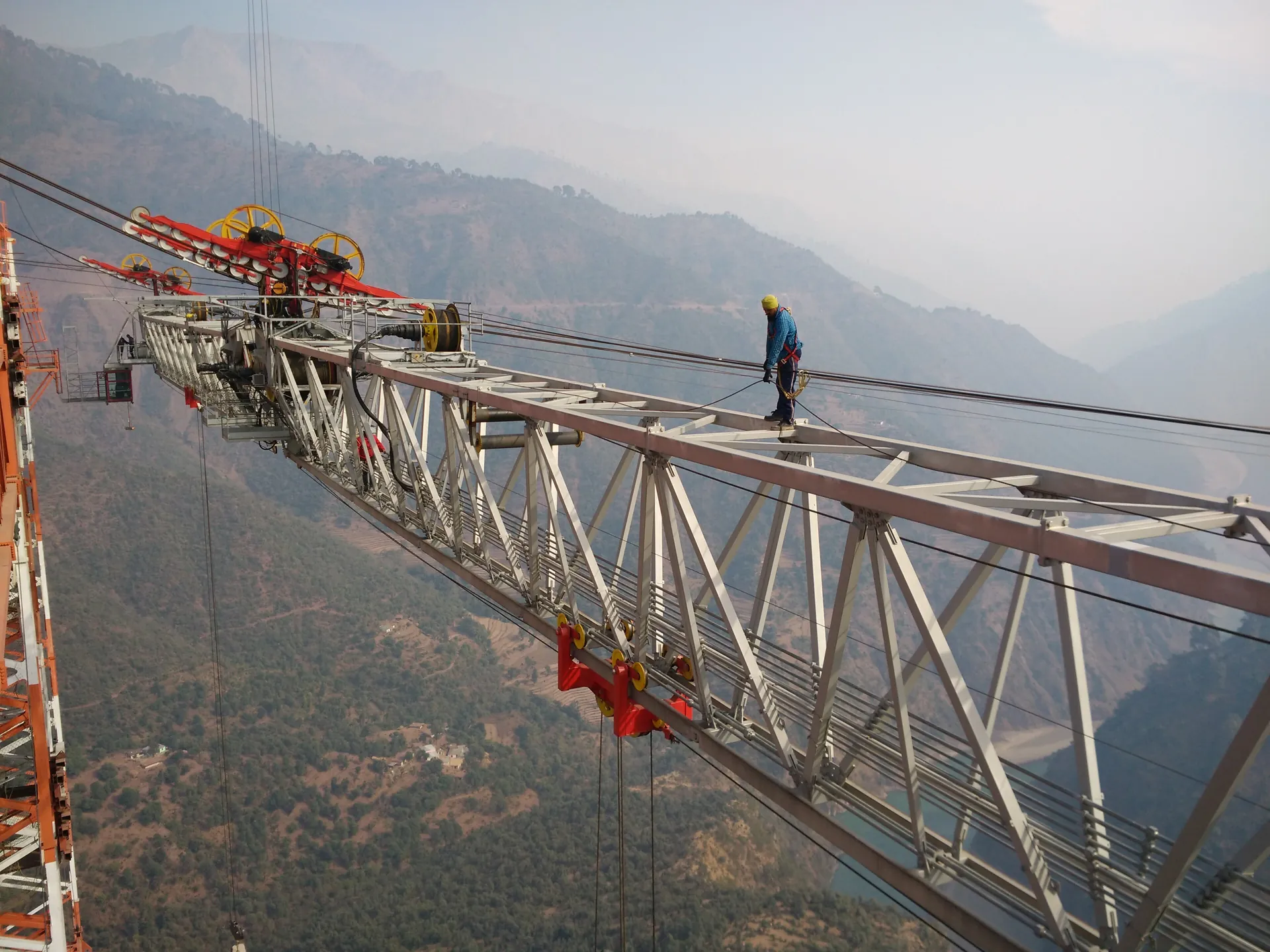 A worker walks a steel member of the Chenab Bridge arch high above the misty gorge, in 2016
