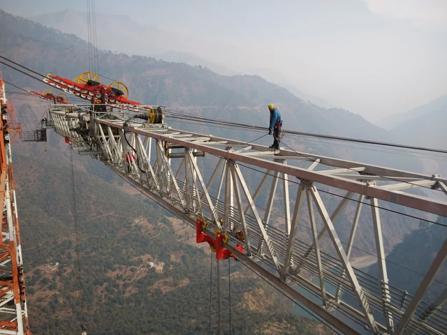 A worker walks a steel member of the Chenab Bridge arch high above the misty gorge, in 2016