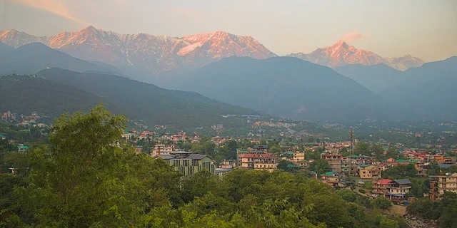 The snow-covered Dhauladhar range glowing pink at dusk above the town of Dharamshala