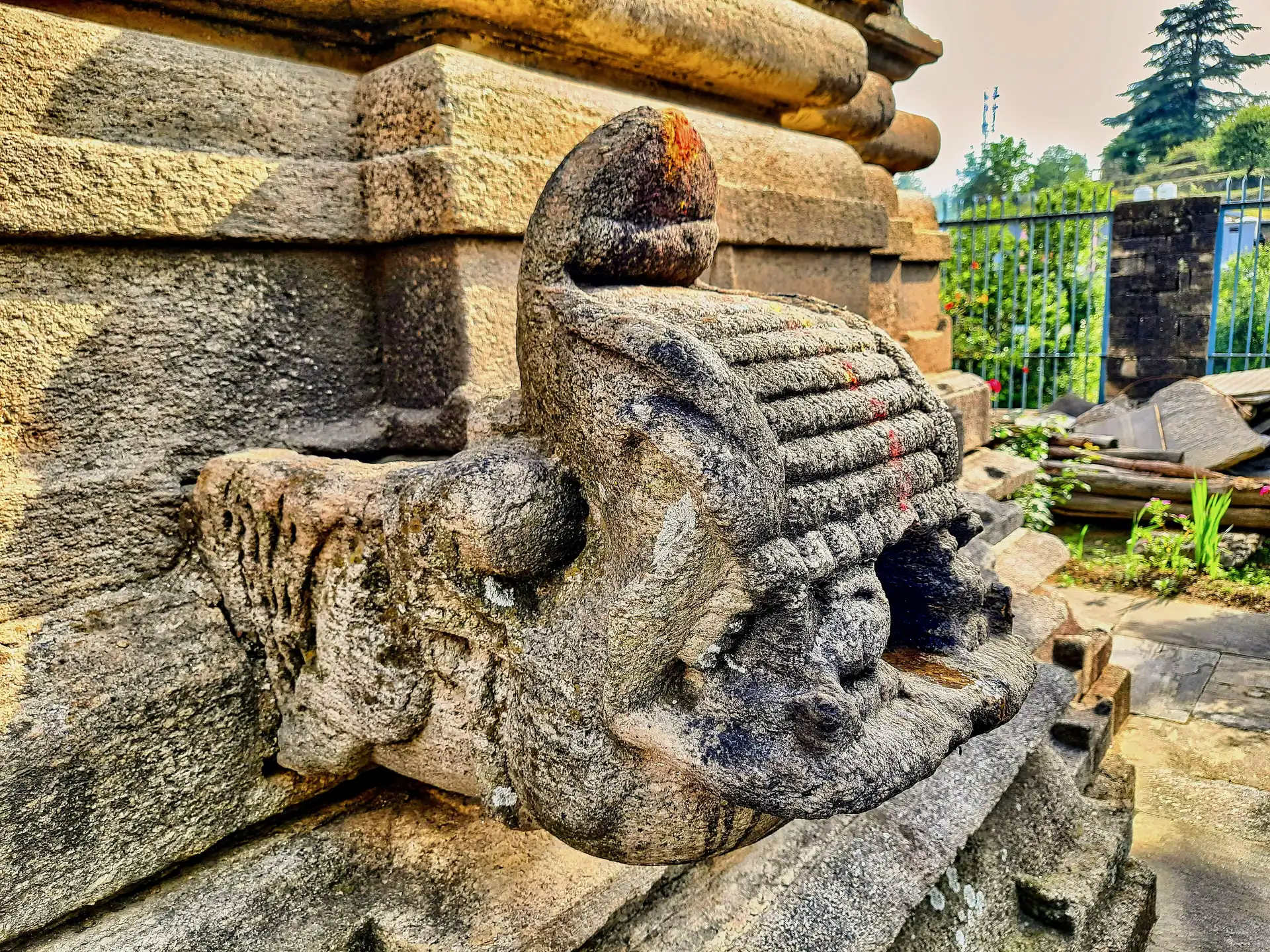 A weathered carved stone lion-like figure on a temple wall at the Badrinath group of temples in Dwarahat
