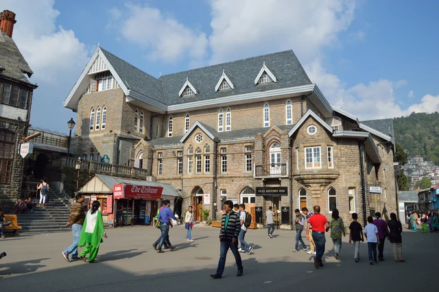 The stone front of the Gaiety Theatre on the Mall in Shimla, with gabled slate roofs and people crossing the square