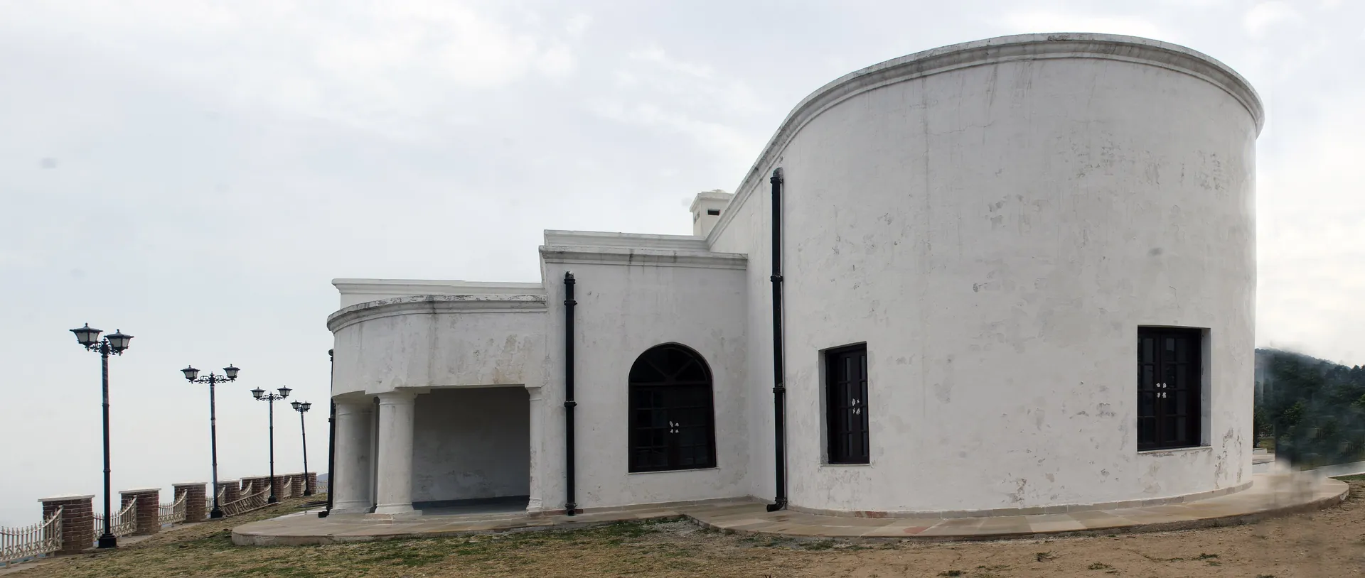 The whitewashed curved end of the Everest house at Park Estate, with a row of lamp posts along a paved terrace