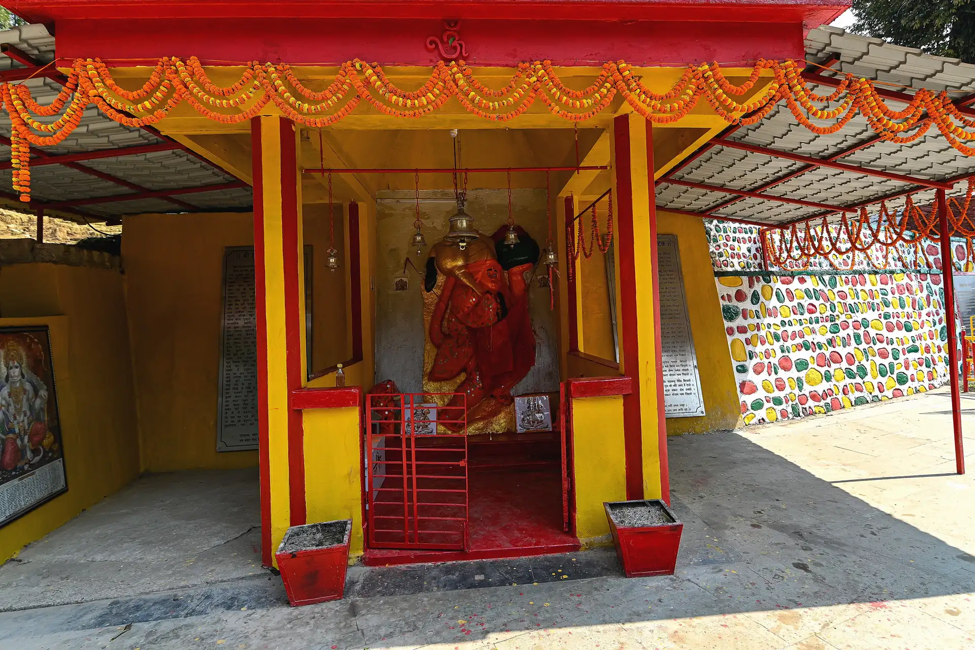 The white-and-red domed Hanuman Tok temple behind a wide paved forecourt with tall conifers and a blue sky