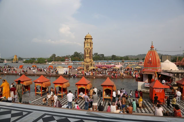 The ghats of Har Ki Pauri on the Ganga, with the clock tower, small red-roofed shrines and bathers on the steps