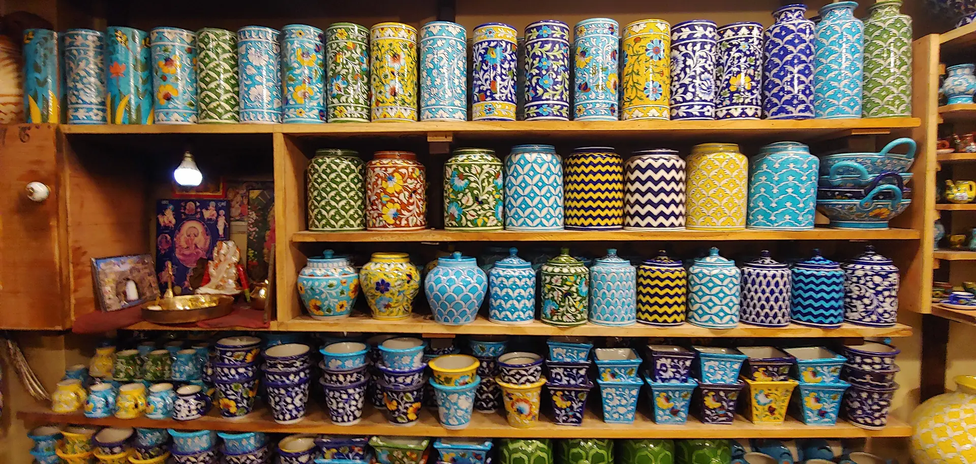 Shelves of Jaipur blue pottery jars and vases in blue, turquoise, yellow and green patterns in a Jaipur shop