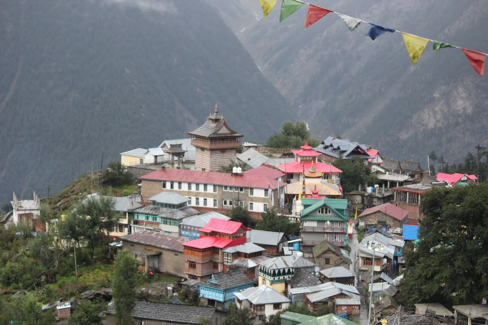 The old village of Chini in Kalpa, with a fort tower above the rooftops and prayer flags in front