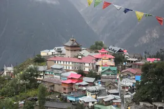 The old village of Chini in Kalpa, with a fort tower above the rooftops and prayer flags in front