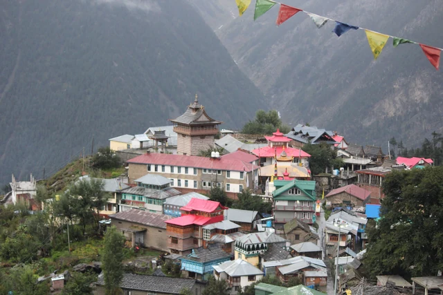 The old village of Chini in Kalpa, with a fort tower above the rooftops and prayer flags in front