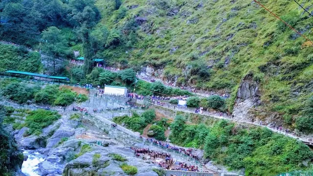 The trail leaving the hamlet of Gaurikund beside a river, with steep green slopes above