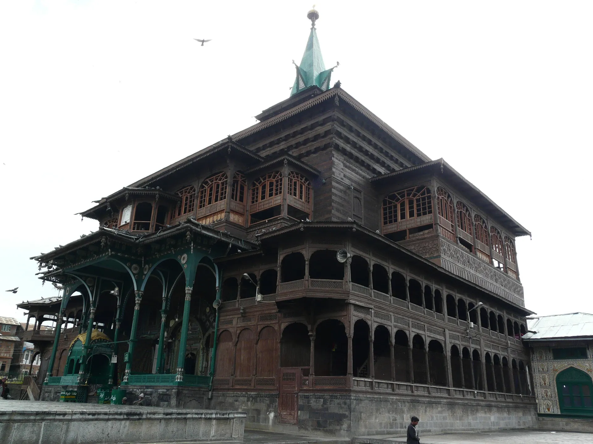 The tall wooden Khanqah-e-Moula with its carved balconies and a spired pagoda roof against the sky