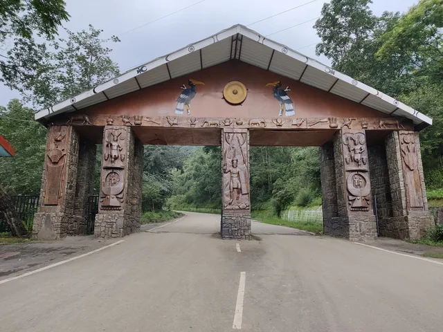 A carved wooden gateway with Naga motifs and a sloping roof over the road into the Kisama Heritage Village