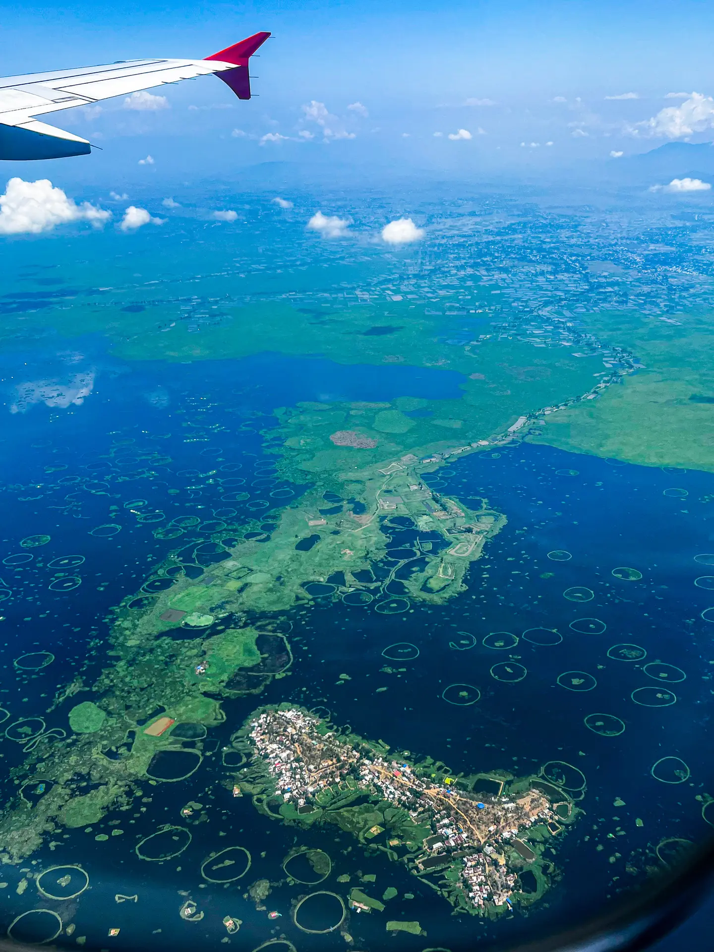 Loktak Lake in Manipur seen from a plane window, dotted with green floating islands and rings of phumdi