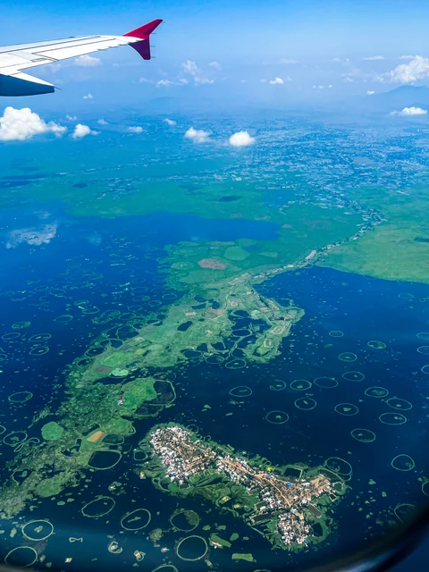 Loktak Lake in Manipur seen from a plane window, dotted with green floating islands and rings of phumdi