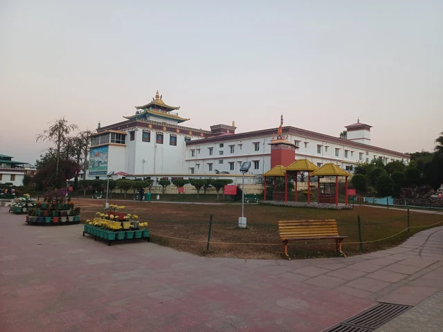 The white and red Mindrolling monastery building with a Tibetan-style roof across a paved garden at dusk