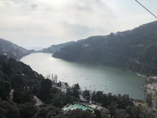 The crescent of Nainital Lake seen from above, with boats on the water and forested slopes on both sides