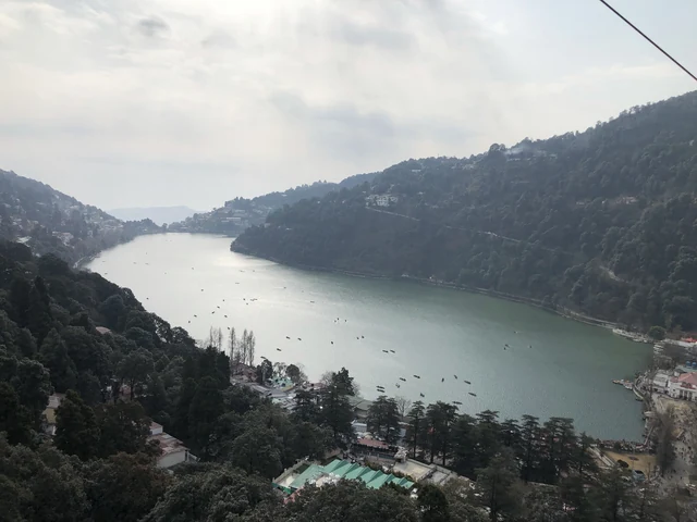 The crescent of Nainital Lake seen from above, with boats on the water and forested slopes on both sides