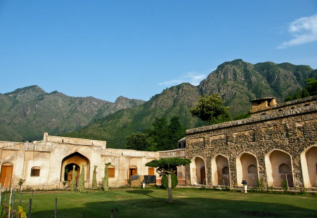 The arched stone terraces of Pari Mahal on a hillside with steep mountains behind under a blue sky