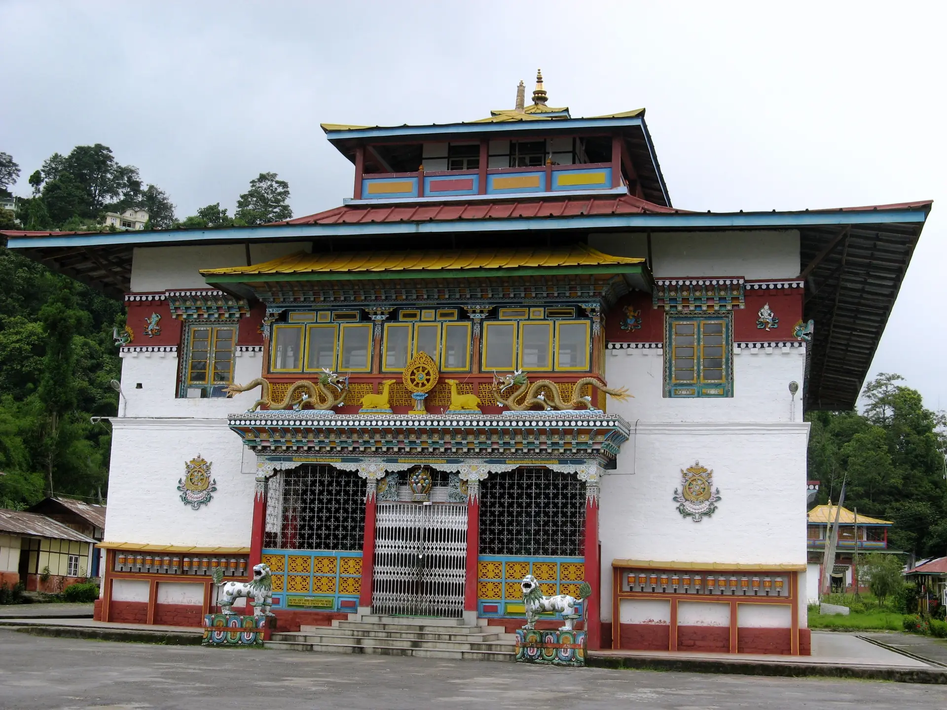 The white, red and gold front of Phodong Monastery with a blue-roofed upper hall, steps and a paved forecourt