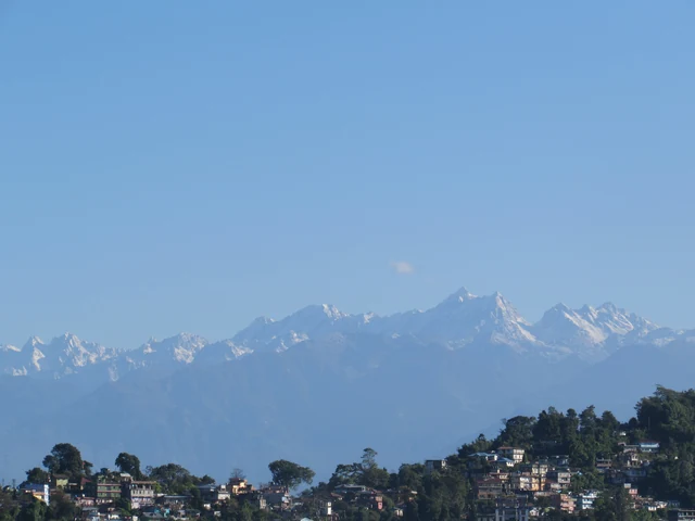 A long snow-covered range under a clear blue sky above the roofs of a hill town