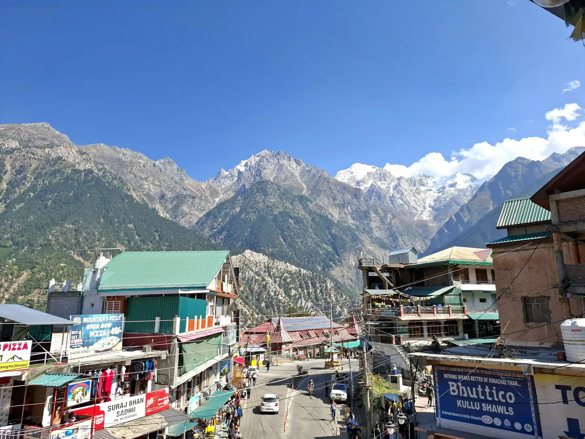 The market street of Reckong Peo, with shops and houses below snow-dusted mountains