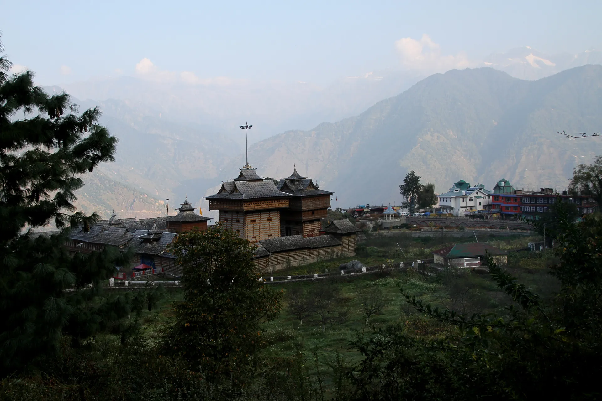 The Bhimakali Temple among trees above the valley, with mountains in the haze beyond
